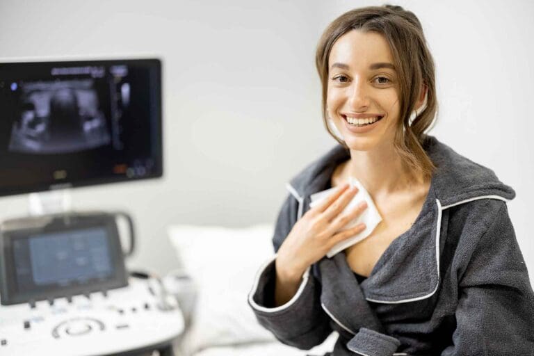 A smiling patient wipes off gel after a clear follow-up ultrasound of the thyroid