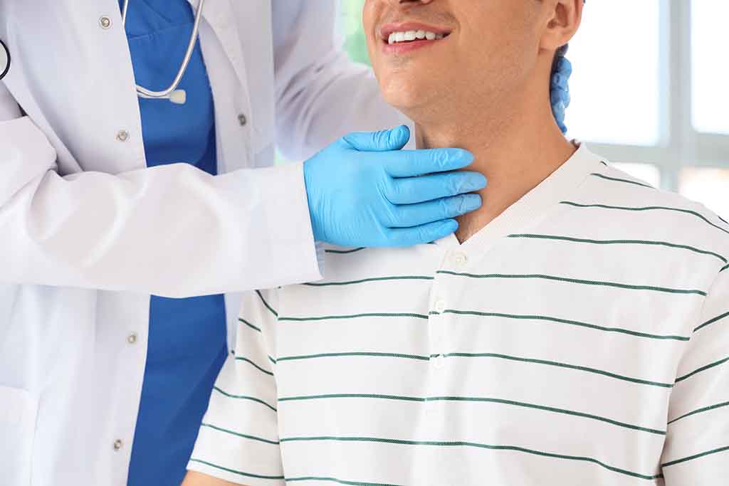 A smiling thyroid patient undergoes palpation during a post-RFA procedure follow-up exam.