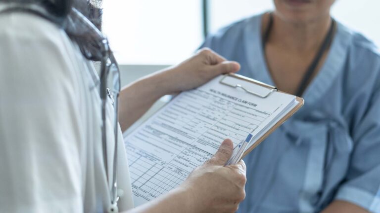 A clinician goes over an insurance claim form with a patient before a procedure