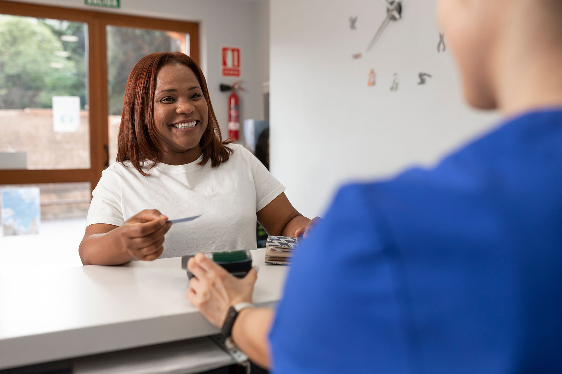 A smiling patient pays for treatment at a medical office